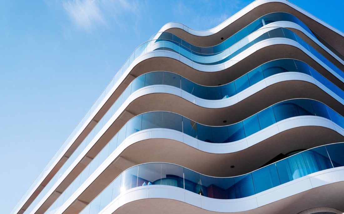 Modern commercial building with curved balconies against a blue sky