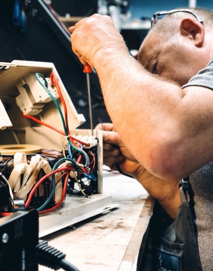 Electrician wiring a control box by hand at a workbench