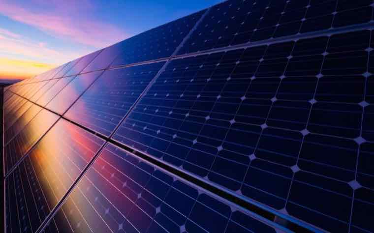 Rows of solar photovoltaic panels reflecting a colorful sky
