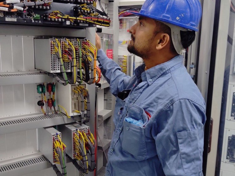 Technician checking wiring and breakers inside a control panel during a storage install